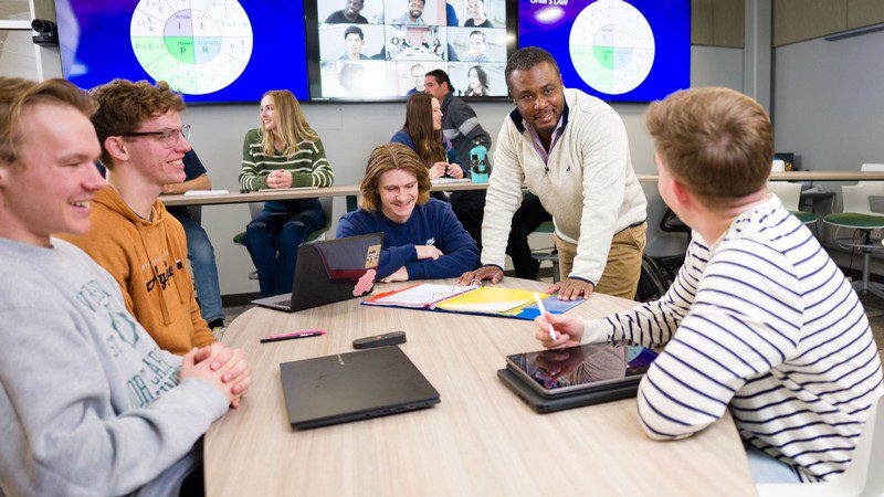 Students at Utah State University engaged in collaborative learning with faculty, showcasing interactive education and digital technology integration
